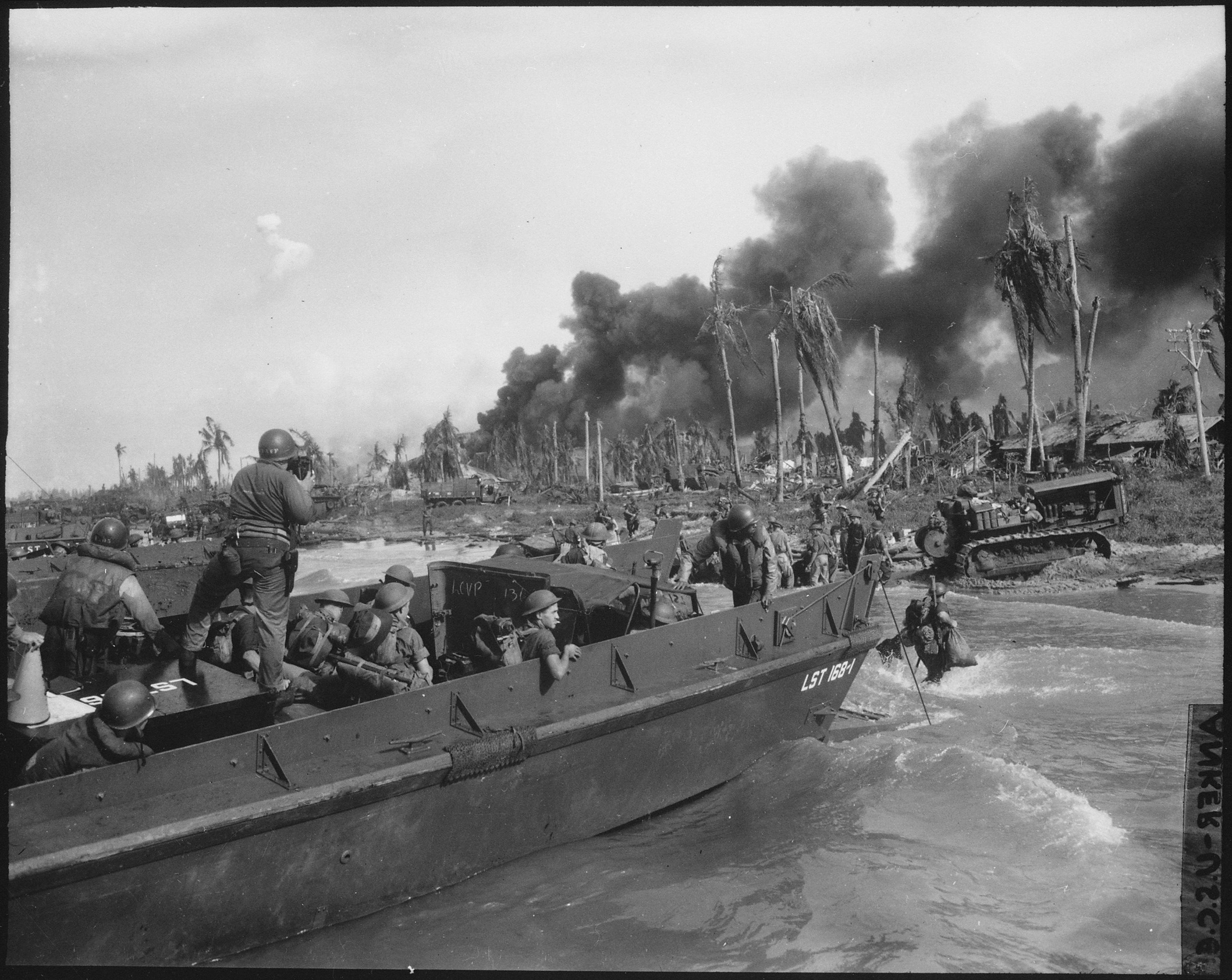 Australian troops storm ashore in the first assault wave to hit Balikpapan on the southeast coast of oil-rich Borneo. Coast Guard Combat Photographer James L. Lonergan stands in the landing craft.