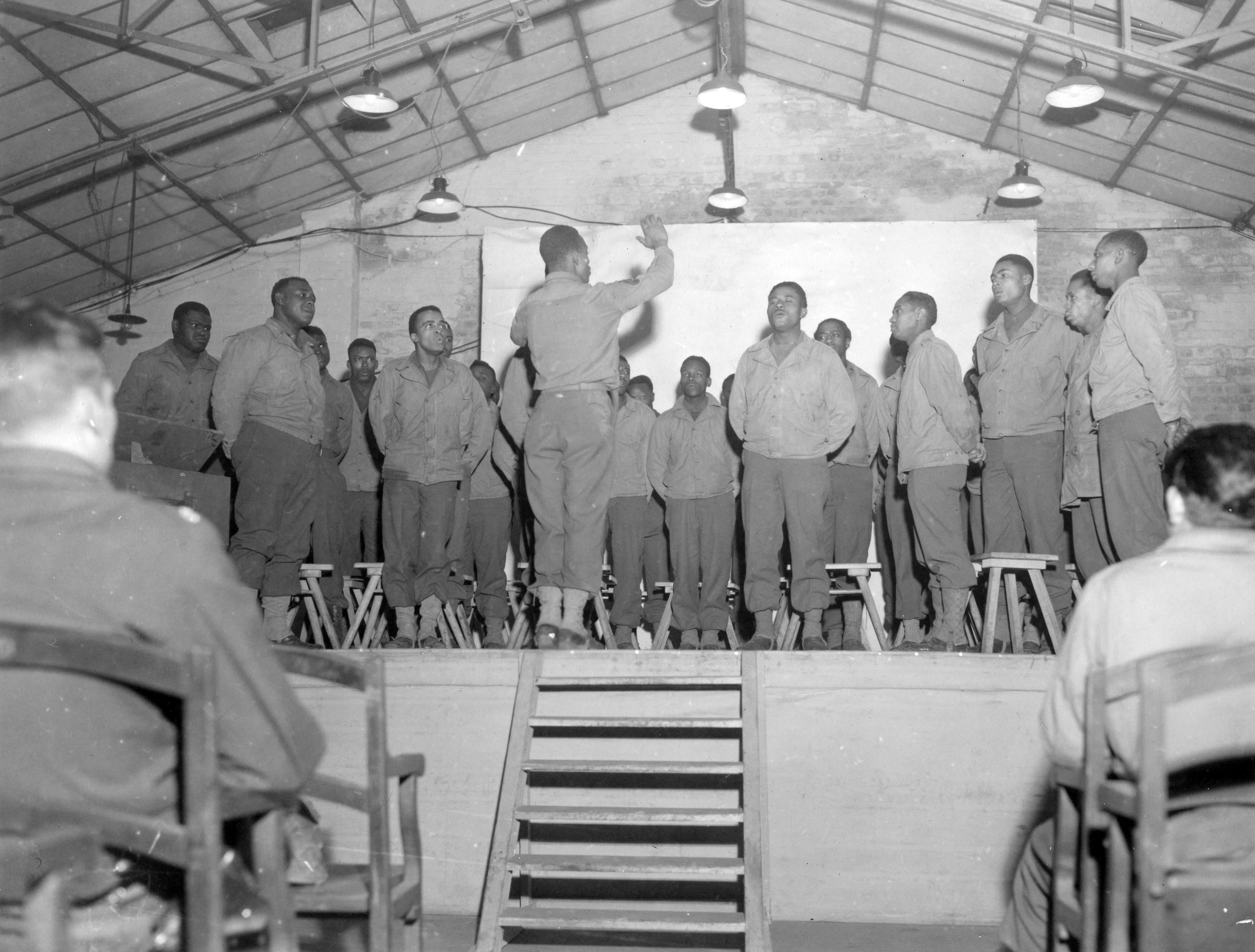 Historical image showing GI chorus entertains U.S. troops at large HQ in Belgium on Christmas Eve. of Black American soldiers during WWII