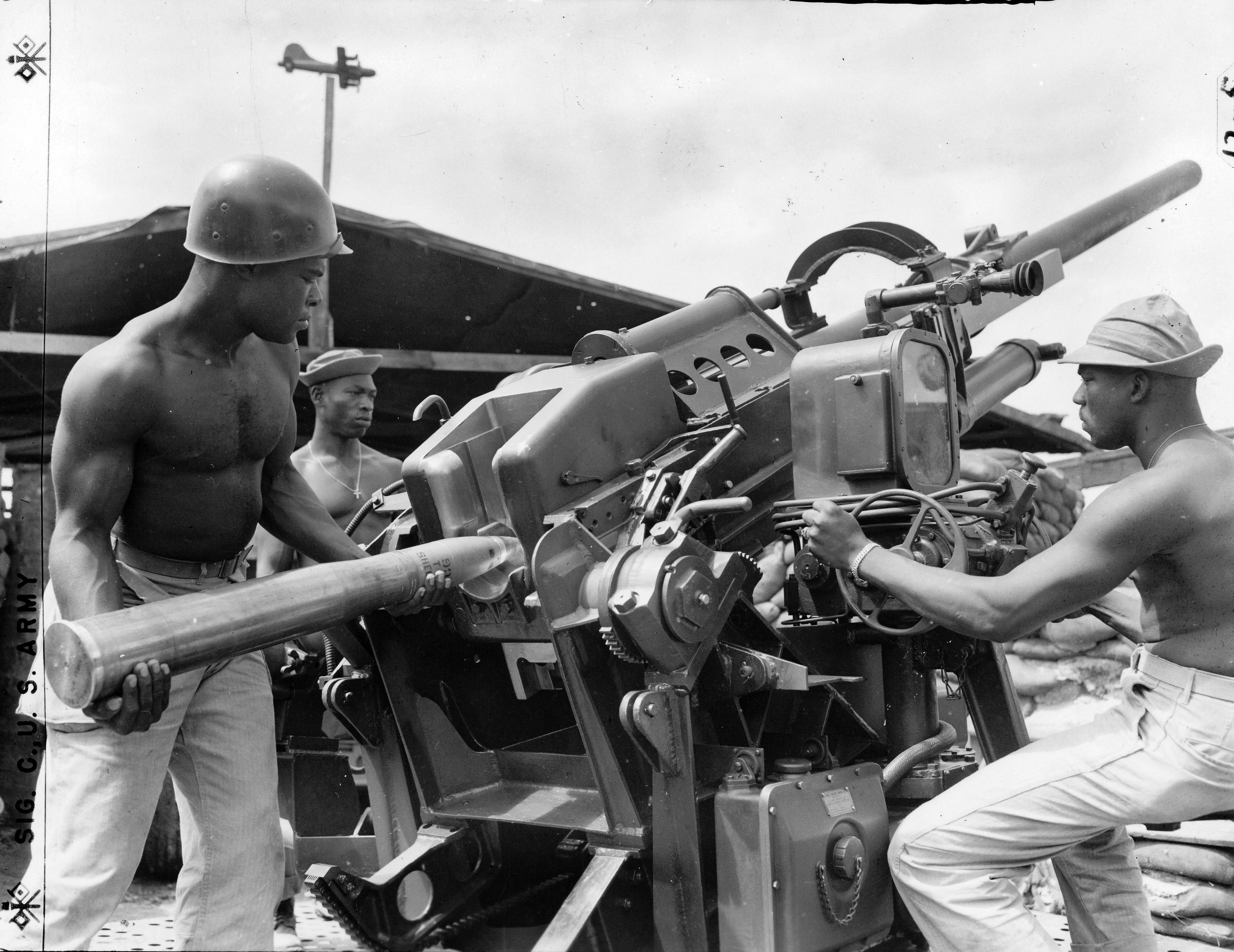 Historical image showing Corporal David Shanks, gunner; and Sgt. Harold Edwards, on elevation of #3 90mm AA gun position of Btry. D, 742nd AA Battalion. of Black American soldiers during WWII