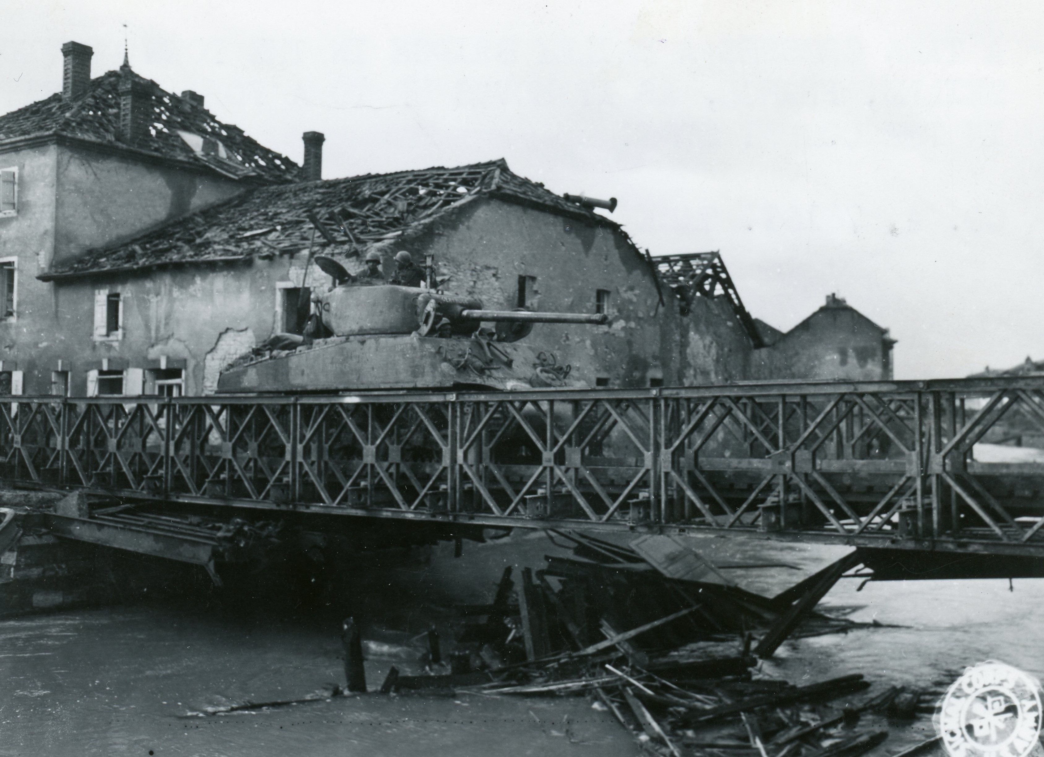 Historical image showing A M4 Sherman tank of the 761st Tank Battalion is crossing a Bailey Bridge in France of Black American soldiers during WWII