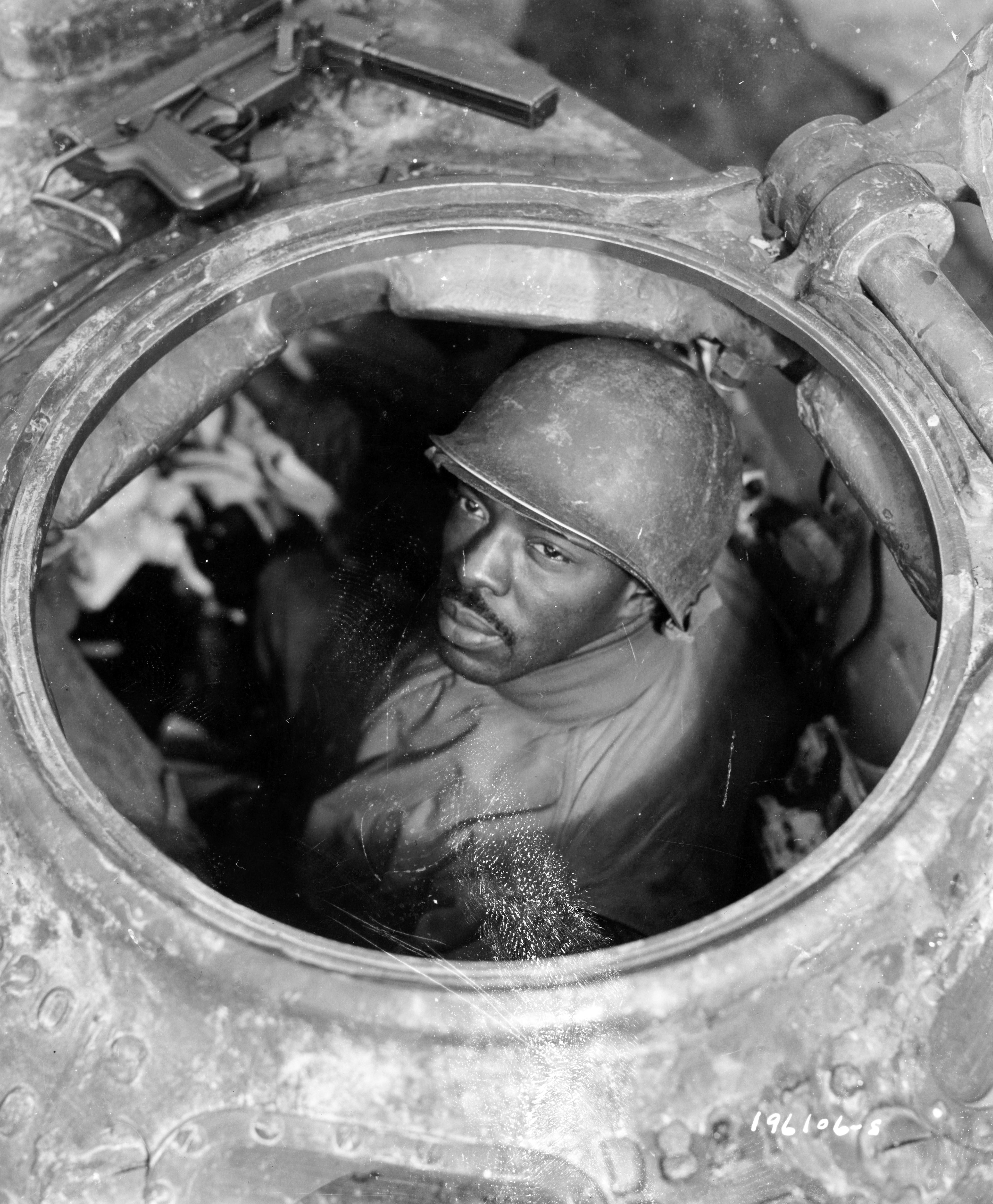 Historical image showing T/4 Claude Mann, Chicago, ILL, is the driver of an M-4 tank attached to a motor transport unit, near Nacy, France. of Black American soldiers during WWII
