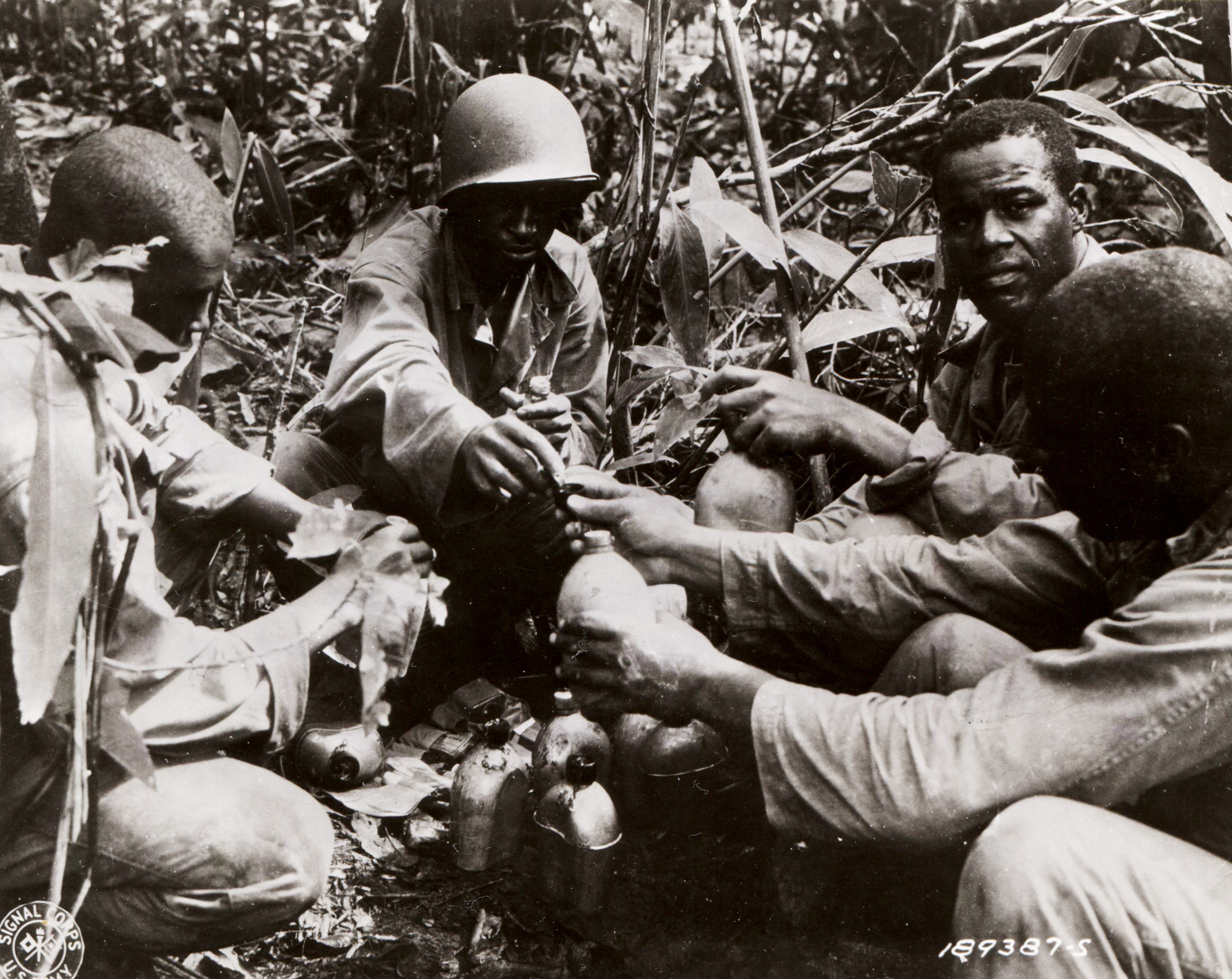 Historical image showing 93rd Infantry Division soldiers purify their drinking water of Black American soldiers during WWII