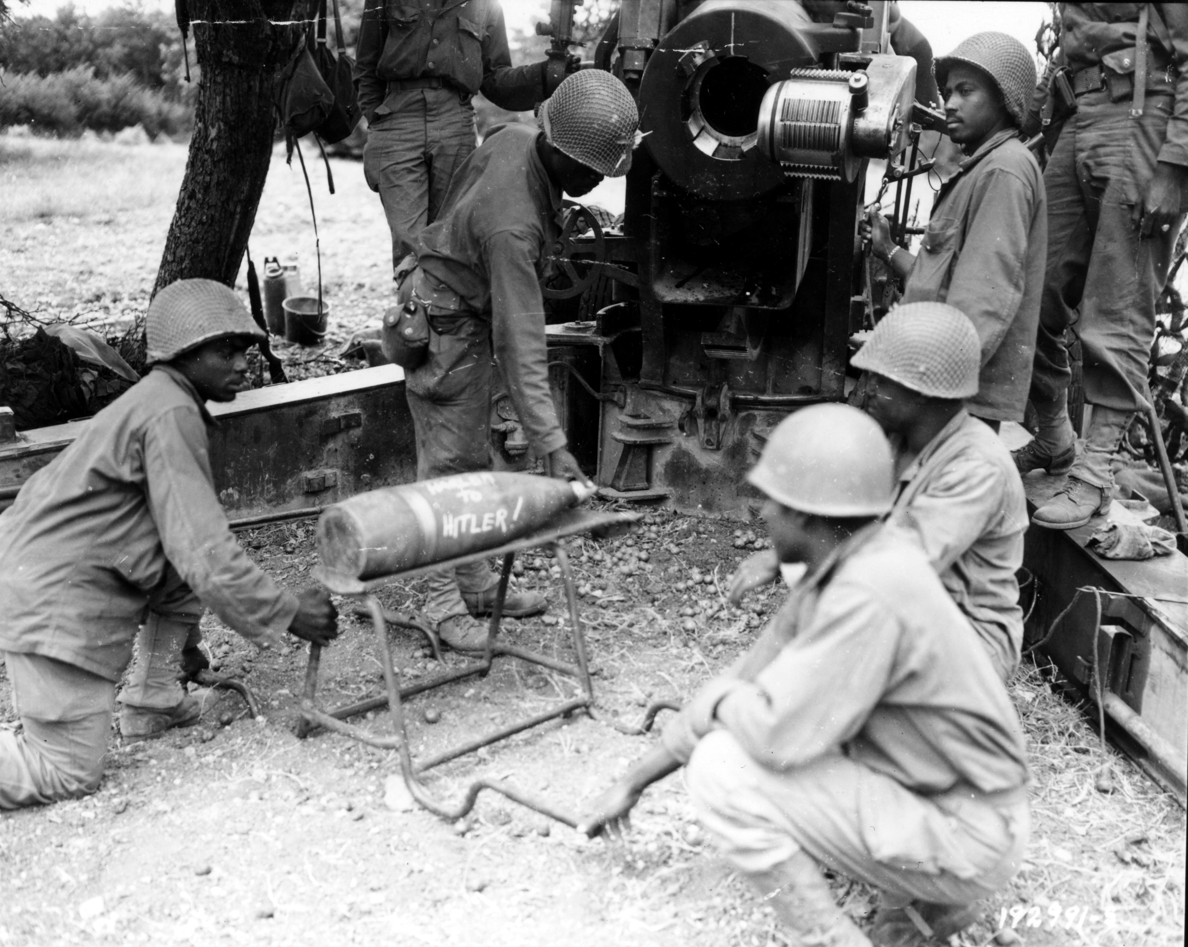 Historical image showing Another present from "Harlem to Hitler" is presented on behalf of an artillery outfit firing at German escape barges across the River Seine. of Black American soldiers during WWII