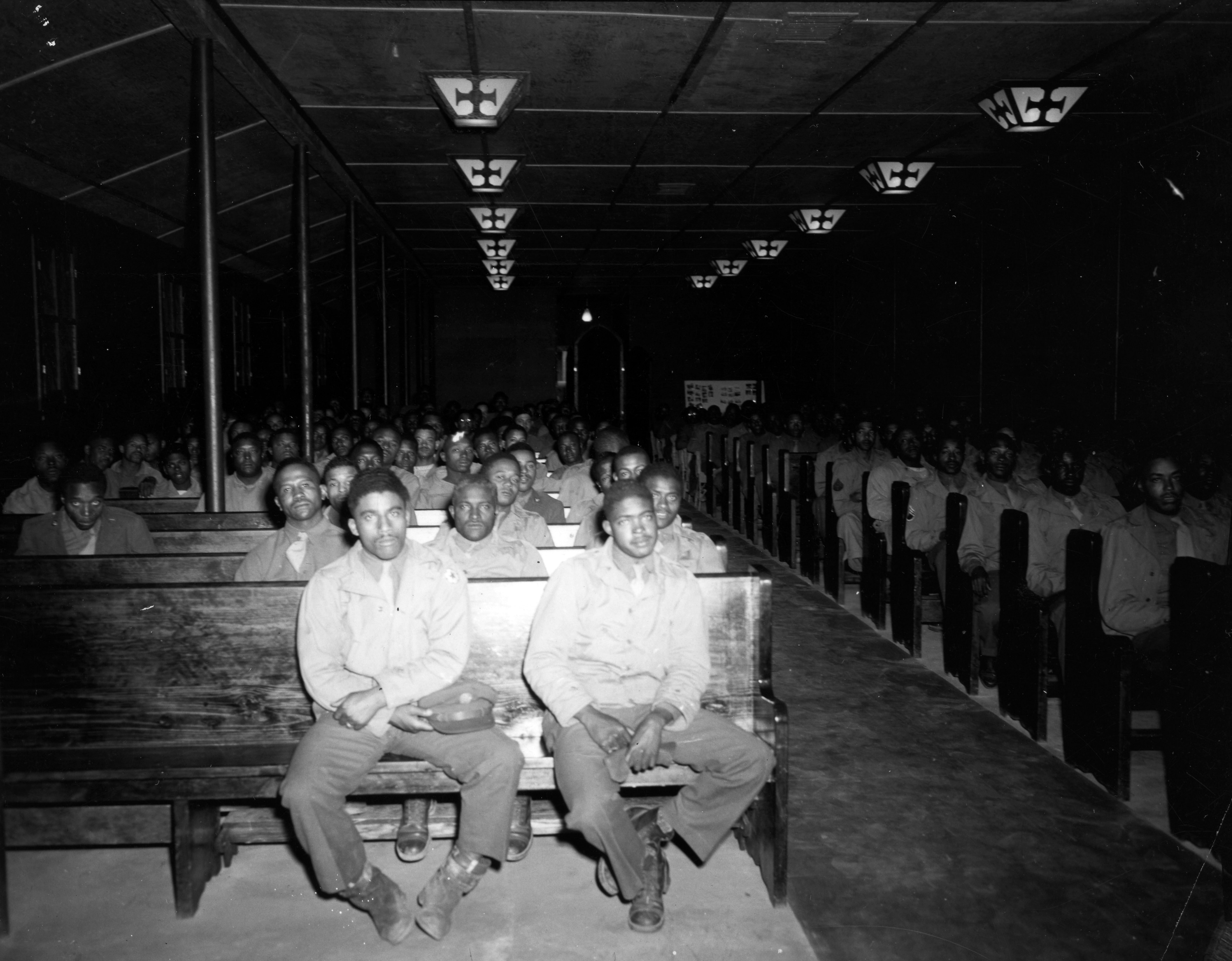 Historical image showing The post chapel has large crowd of Black troops in afternoon of Bishop Gregg sermon. of Black American soldiers during WWII