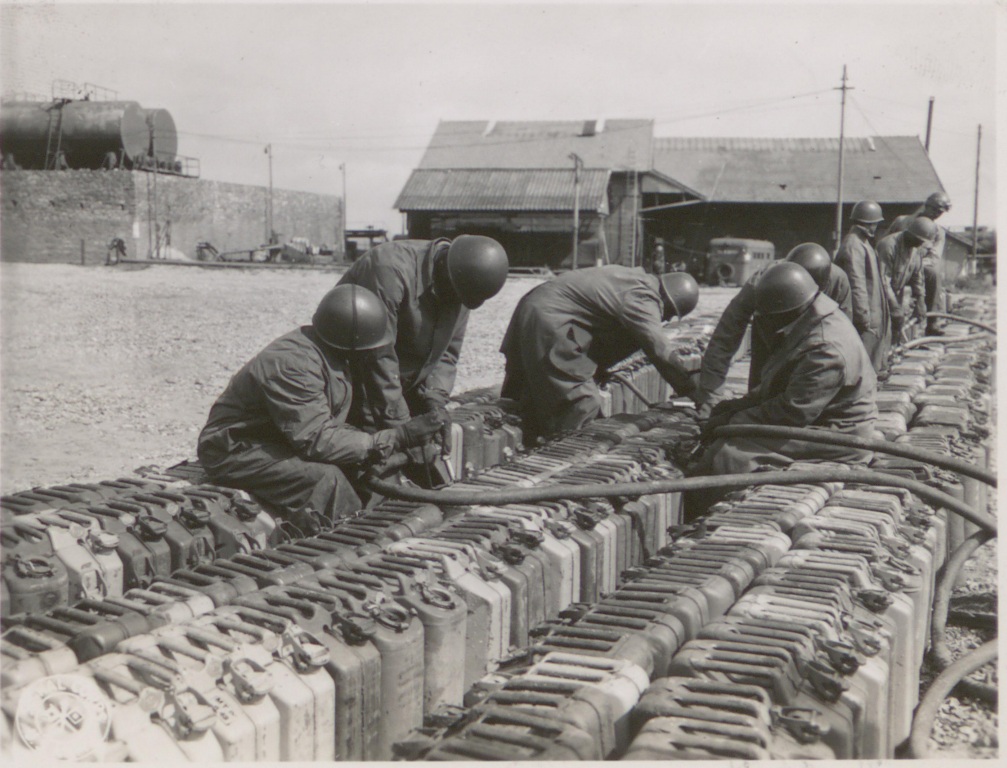 Historical image showing Quartermaster Corps soldiers are filling fuel cans of Black American soldiers during WWII