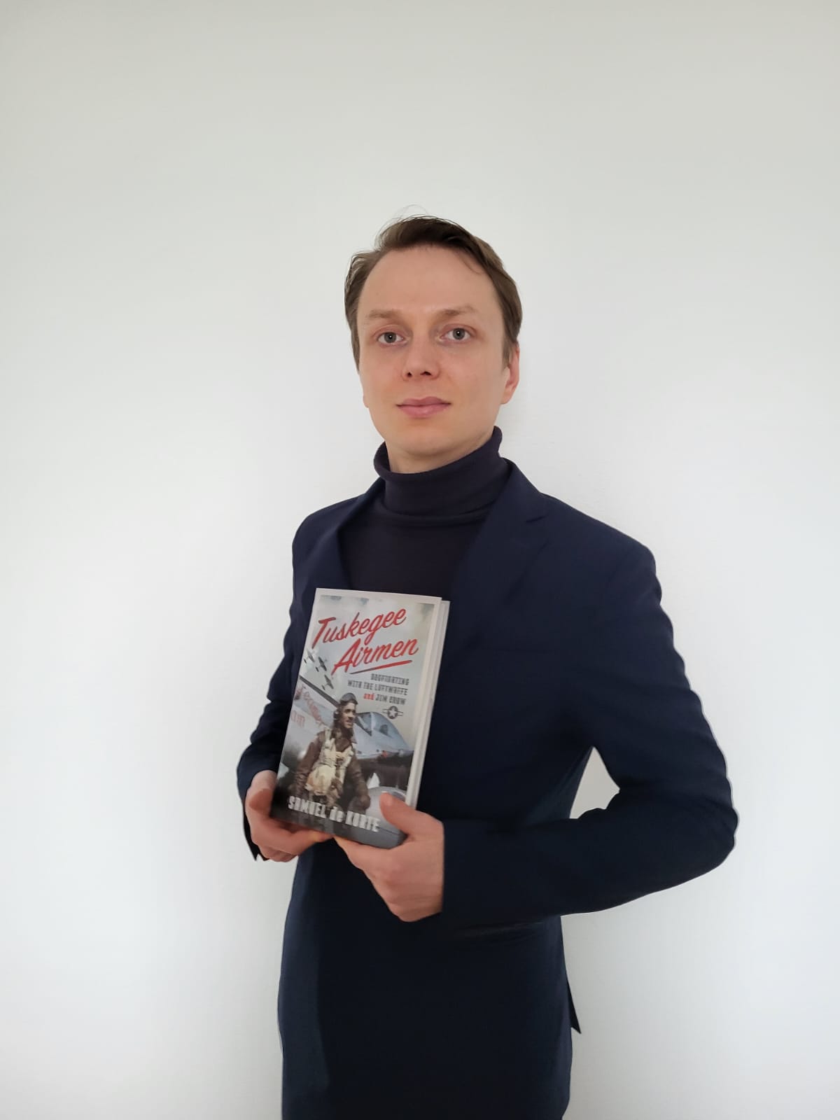 A photograph of Samuel de Korte with his book on the Tuskegee Airmen.